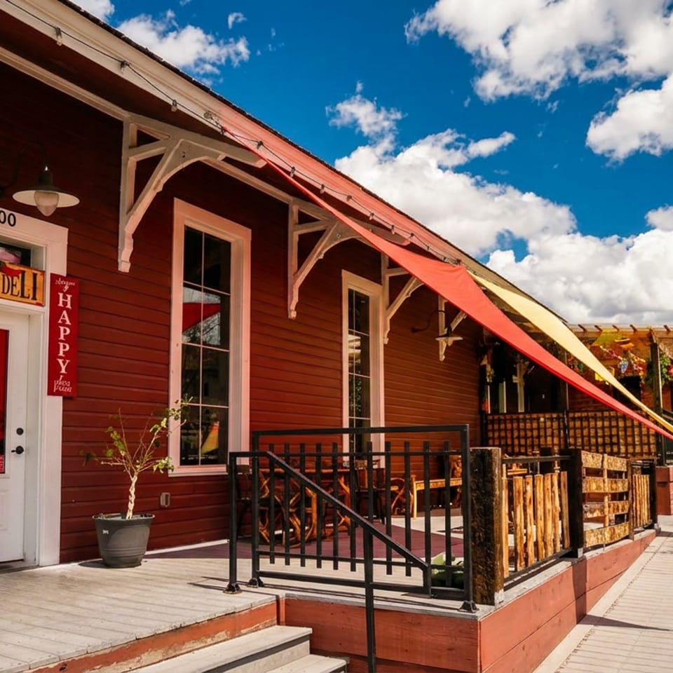 Exterior of Casa Deli, a red building with a white door, outdoor patio, and colorful awnings.